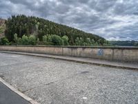 concrete walkway with trees and fenced in area on opposite sides of the road and one side of the road