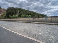 concrete walkway with trees and fenced in area on opposite sides of the road and one side of the road