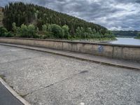 concrete walkway with trees and fenced in area on opposite sides of the road and one side of the road