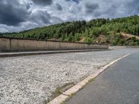 concrete walkway with trees and fenced in area on opposite sides of the road and one side of the road