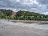 concrete walkway with trees and fenced in area on opposite sides of the road and one side of the road