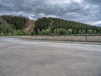 concrete walkway with trees and fenced in area on opposite sides of the road and one side of the road