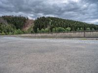 concrete walkway with trees and fenced in area on opposite sides of the road and one side of the road