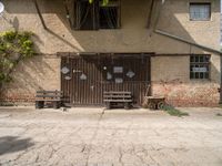 two benches sit in front of a wall covered with ivys and a door with signs