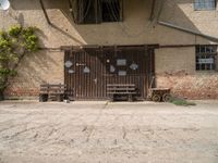 two benches sit in front of a wall covered with ivys and a door with signs