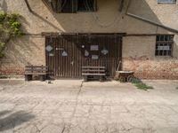 two benches sit in front of a wall covered with ivys and a door with signs