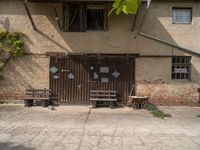 two benches sit in front of a wall covered with ivys and a door with signs