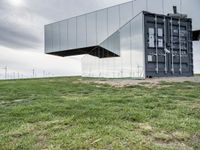 two buildings that are sitting in the grass outside of them with wind turbines behind them