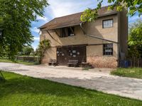 an old house next to a sidewalk in a country setting with a fence around it