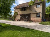 an old house next to a sidewalk in a country setting with a fence around it