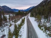 a road with a single car on it and a mountainside in the background at dusk