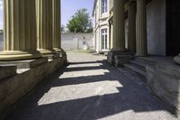 a hallway in an historic building next to pillars with columns in the middle and a stone bench on the ground below