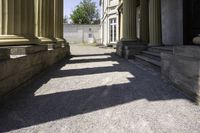 a hallway in an historic building next to pillars with columns in the middle and a stone bench on the ground below