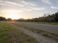 a stop sign sits on a rural highway at sunset with mountains in the background under a blue sky