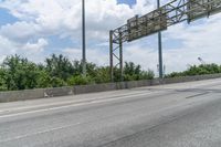 a highway with an overpass between the two lanes that have trees in the background