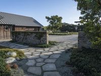 an open pathway in front of a building with a slate roof and stone walkway that leads to two entrances