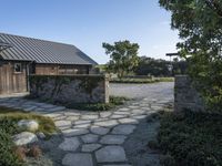 an open pathway in front of a building with a slate roof and stone walkway that leads to two entrances