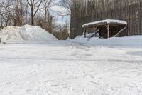 the house is made of wood, covered with snow and surrounded by piles of dirt