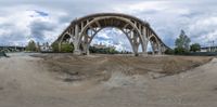 a panorama time lapse image shows construction in progress at an intersection with bridges in the background