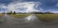 an intersection with a house in the background and mountains in the distance seen through a fish eye lens