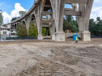 a construction site under the interstate bridge with several buildings below it and trees around the perimeter