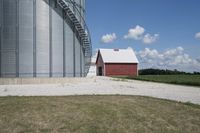 the barn is next to the silo on a clear day, with clouds in the sky