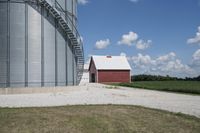 the barn is next to the silo on a clear day, with clouds in the sky