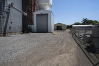 a farm is parked behind a chain link fence near a silo and warehouse building