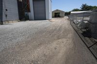 a farm is parked behind a chain link fence near a silo and warehouse building