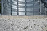 a couple of large metal storage tanks with plants growing out the bottom and grass on the ground