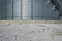 a couple of large metal storage tanks with plants growing out the bottom and grass on the ground