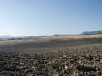 a view from a distance looking at the land of a plowed field and hills