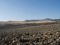 a view from a distance looking at the land of a plowed field and hills