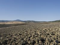 a view from a distance looking at the land of a plowed field and hills