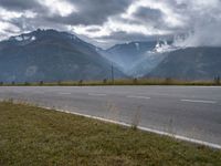 a red van is driving on the road near mountains with clouds in the sky over a valley