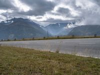 a red van is driving on the road near mountains with clouds in the sky over a valley