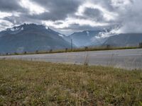 a red van is driving on the road near mountains with clouds in the sky over a valley