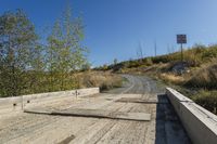 an empty road is shown next to the grass and rocks in the distance are some trees