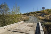 an empty road is shown next to the grass and rocks in the distance are some trees