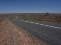 a paved road in the middle of an open desert plain on a clear day, with no cars