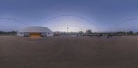 an outdoor area with dirt roads, and a white building and string lights in the sky