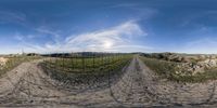 a dirt road runs through a field with barbed wire fencing around it and a hillside