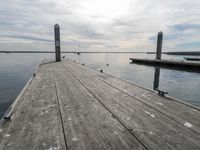 a dock surrounded by wooden boards in the water and birds on the dock nearby to the water