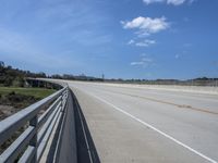 the bridge is surrounded by a long strip of dirt and grass that stretches into the distance