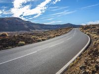 this is a picture of the desert road in the middle of nowhere with rocks and grass around