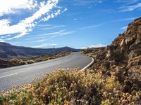 this is a picture of the desert road in the middle of nowhere with rocks and grass around