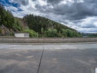 concrete walkway with trees and fenced in area on opposite sides of the road and one side of the road