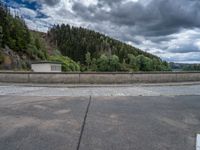 concrete walkway with trees and fenced in area on opposite sides of the road and one side of the road