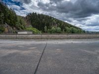 concrete walkway with trees and fenced in area on opposite sides of the road and one side of the road