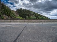 concrete walkway with trees and fenced in area on opposite sides of the road and one side of the road